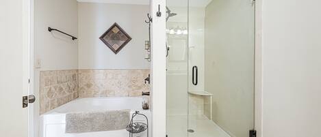 A bathroom with a glass-enclosed shower, a bathtub, and a towel rack.