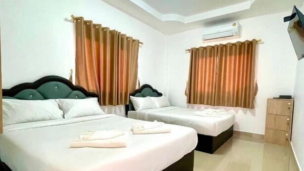 A hotel room with two beds, beige curtains, an air conditioning unit, and a wooden cabinet.