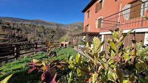 Un bâtiment rustique, doté d’une clôture en bois et d’un jardin en premier plan.