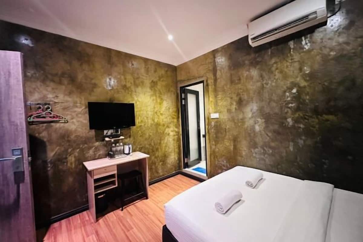 A hotel room with a bed, a television, a small desk, and a wardrobe.