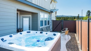 Un patio trasero con un jacuzzi, una silla de jardín y una valla de madera.