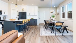 Una cocina moderna con armarios blancos, una isla central e iluminación colgante.