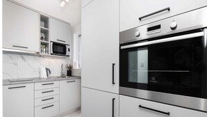 Una cocina moderna con electrodomésticos de acero inoxidable, armarios blancos y una salpicadera de mármol.