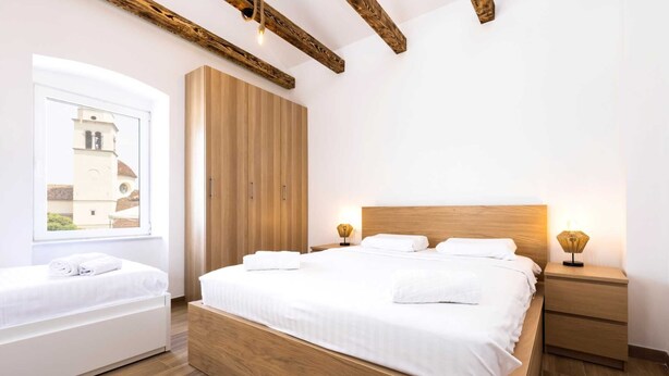 Un dormitorio moderno con una cama grande, un armario de madera y una mesita de noche con lámpara.
