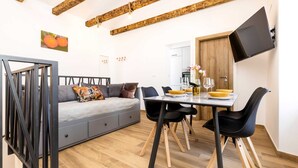Una sala de estar moderna con un sofá gris, sillas negras y una mesa de comedor de madera dispuesta para dos personas.