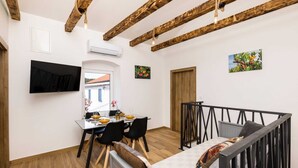 Un comedor con una mesa dispuesta para cuatro personas, un sofá y un televisor montado en la pared.
