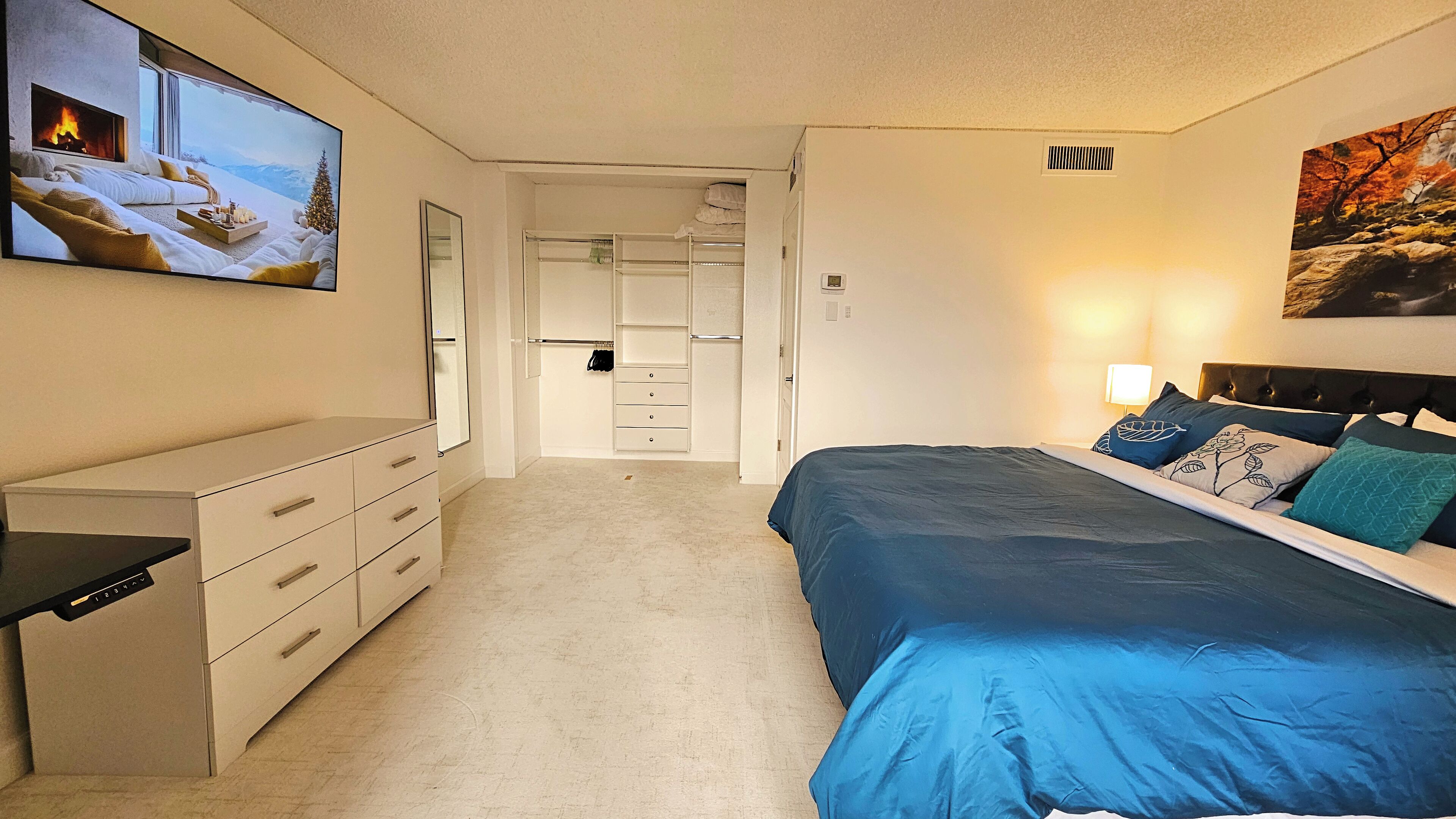 A bedroom with a bed, dresser, and a TV displaying a snowy landscape.