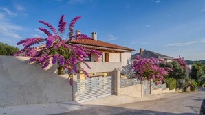 A house with a red-tiled roof, a concrete wall, and a gated entrance. - Cozy 1BR Suite for Three, No Pets, Parking Available (Mali Lošinj)