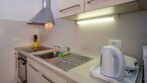 A compact kitchen with a stainless steel sink, a kettle, and a range hood. - Cozy 1BR Suite for Three, No Pets, Parking Available (Mali Lošinj)