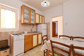 Compact kitchen with gas stove, refrigerator, and dining area with table and chairs.