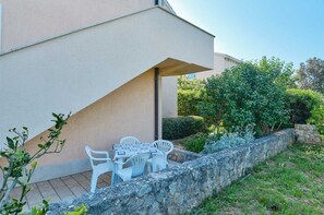 Relax in a serene outdoor space with a table and chairs, surrounded by a stone wall and lush greenery.