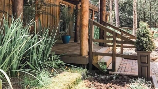 Eine Holzhütte mit Veranda, umgeben von dichtem Wald.