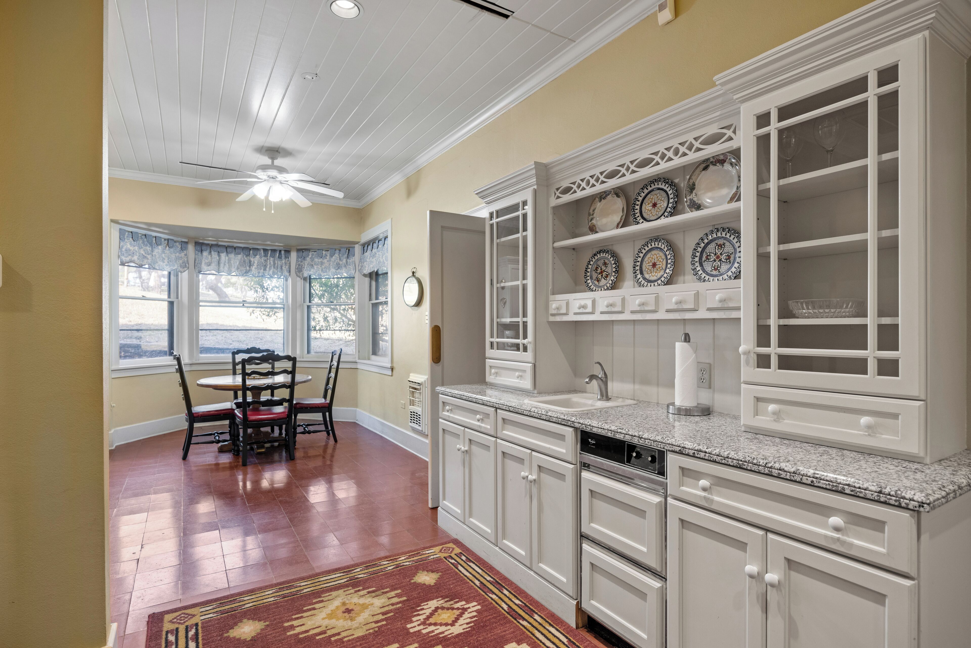 A kitchen with white cabinets, a granite countertop, and a dining area with a table and chairs.