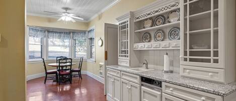 A kitchen with white cabinets, a granite countertop, and a dining area with a table and chairs.