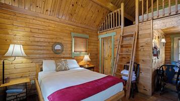 A wooden cabin room with a bed, two bedside tables with lamps, a chair, and a ladder leading to an upper level.