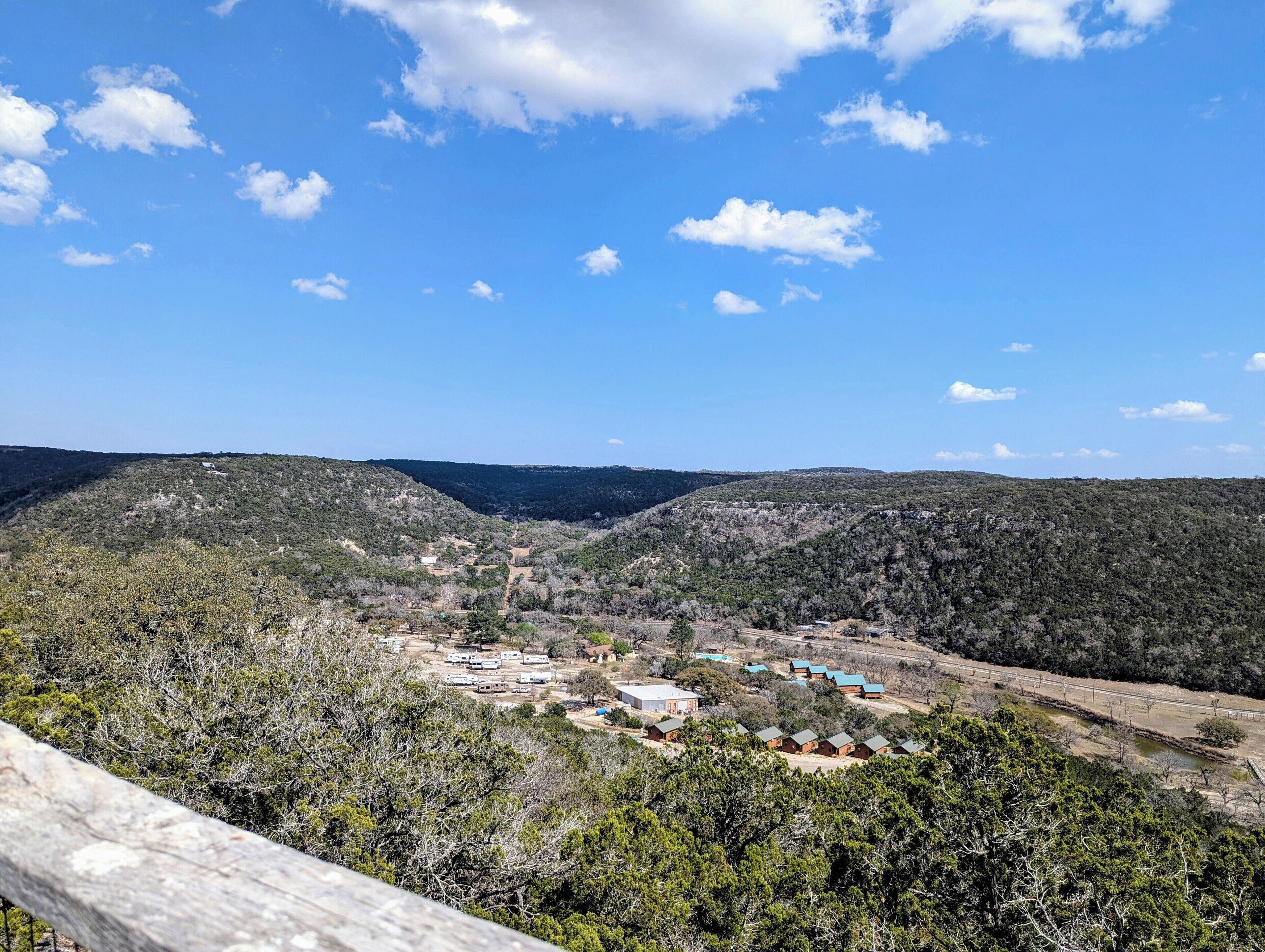 A campsite with multiple cabins and a dirt road leading through a hilly landscape.