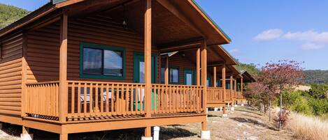 A wooden cabin with a porch, multiple windows, and a clear view of the surrounding landscape.