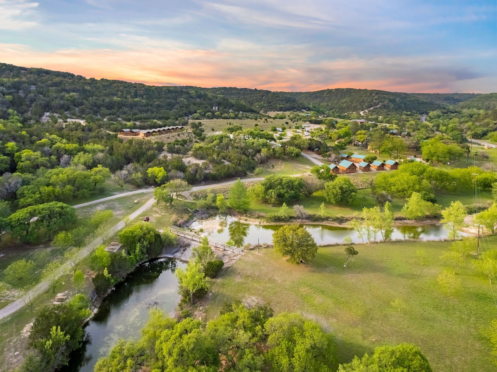 A rural landscape with a river, green fields, and scattered buildings.