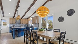 Una cocina moderna con vigas de madera, una isla grande e iluminación colgante.