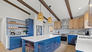 Una cocina moderna con armarios azules, una isla central e iluminación colgante.