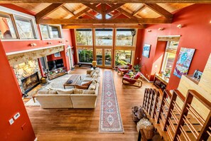 A spacious living room with a fireplace, large windows, and a view of the outdoors.