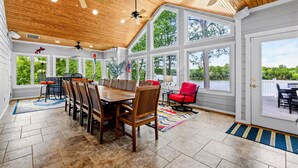 A spacious covered patio with a dining table, chairs, ceiling fans, and large windows offering a view of the outdoors. - Lakefront Lake Anna, Views, Boat Dock, Hot Tub (Mineral)