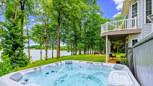 A hot tub surrounded by trees and a lake, with a house in the background. - Lakefront Lake Anna, Views, Boat Dock, Hot Tub (Mineral)