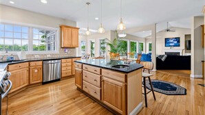 A spacious kitchen with wooden cabinets, a central island, and pendant lighting. - Lakefront Lake Anna, Views, Boat Dock, Hot Tub (Mineral)