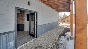 Un bâtiment moderne doté d’un espace extérieur couvert, d’une cheminée en briques et d’un chemin de gravier.