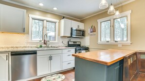 Una cucina moderna con mobili bianchi, lavastoviglie in acciaio inossidabile, forno a microonde e fornello.