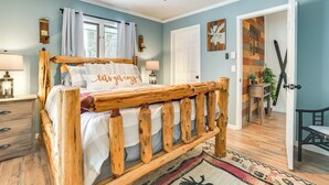 Una camera da letto con un letto di legno, una ventola a soffitto, un comodino, una lampada e una finestra con tende.