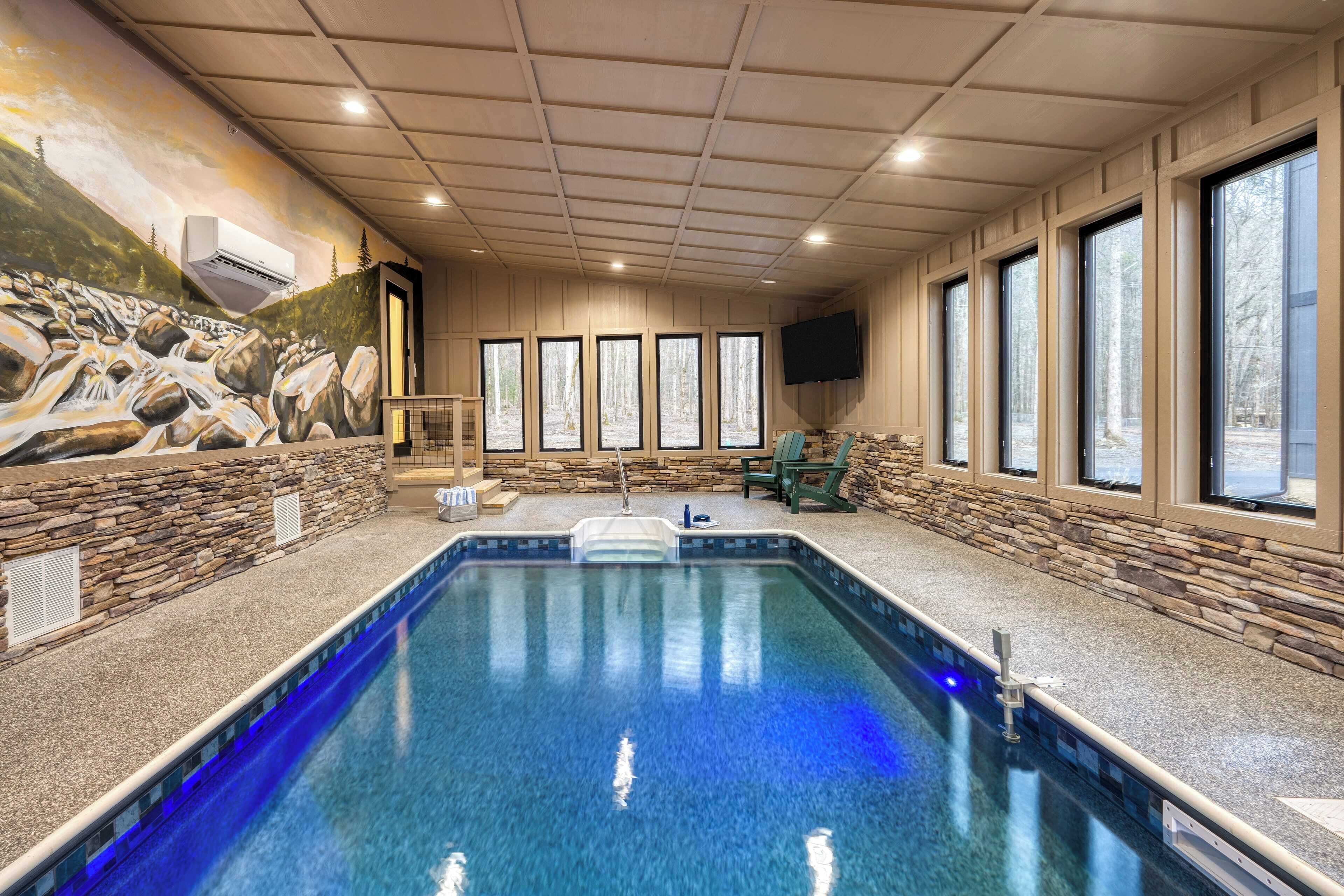 An indoor swimming pool with a stone wall and a mural of a waterfall.