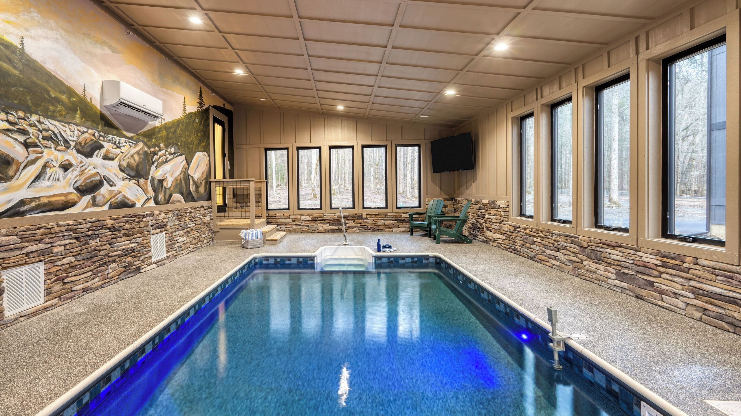 A swimming pool with stone walls and windows, a stone bench, and a mural.
