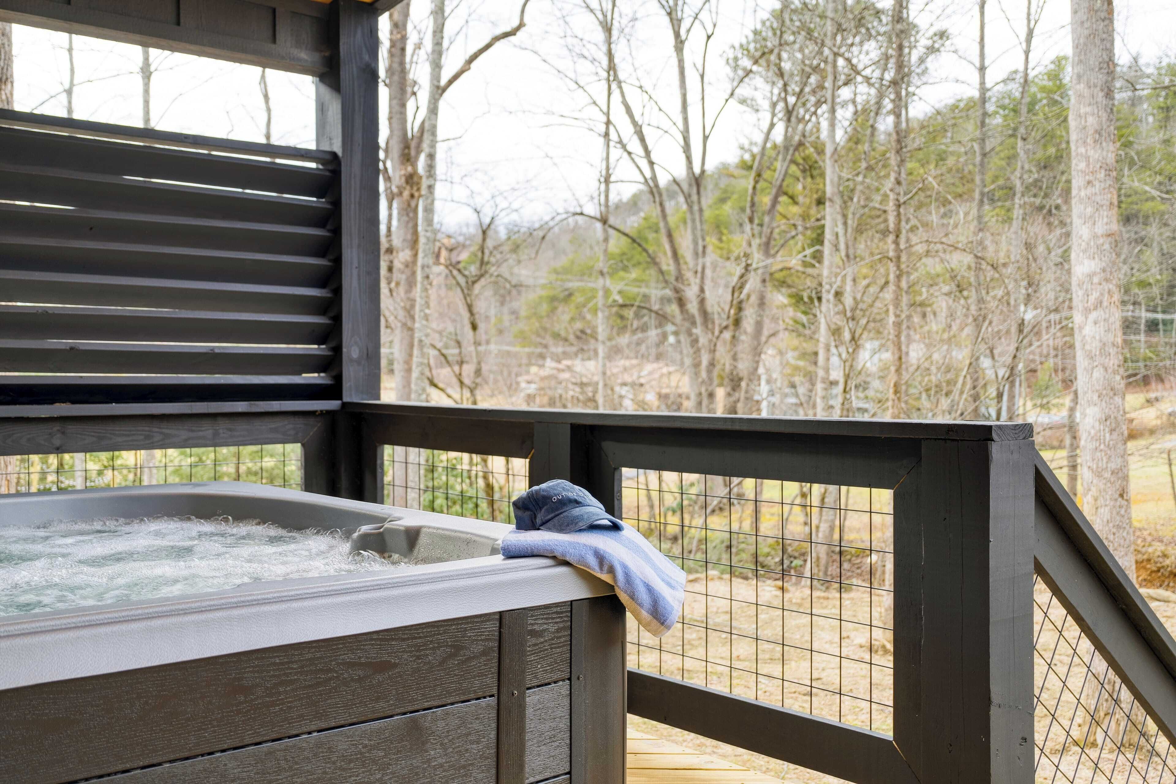 A hot tub with a towel on the edge, surrounded by a wooden deck and a wire fence.