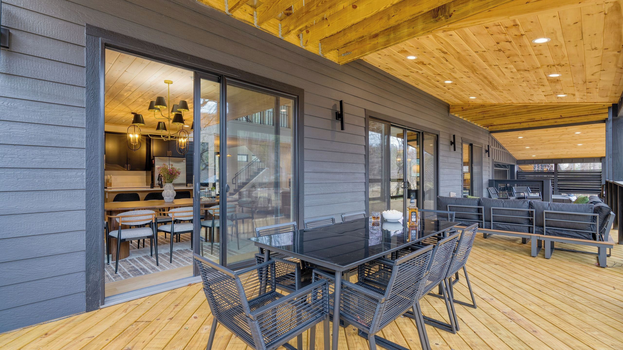 A modern interior with a dining area, kitchen, and a wooden deck.