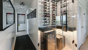 Une chambre d’hôtel moderne dotée d’un meuble à vin, d’une cave à vin intégrée et d’un grand miroir.