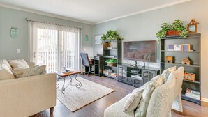 A living room with a sofa, a coffee table, a TV, a bookshelf, and a desk with a chair. - Golf, Shop & Relax Beachside! Hilton Head Getaway (Hilton Head Island)