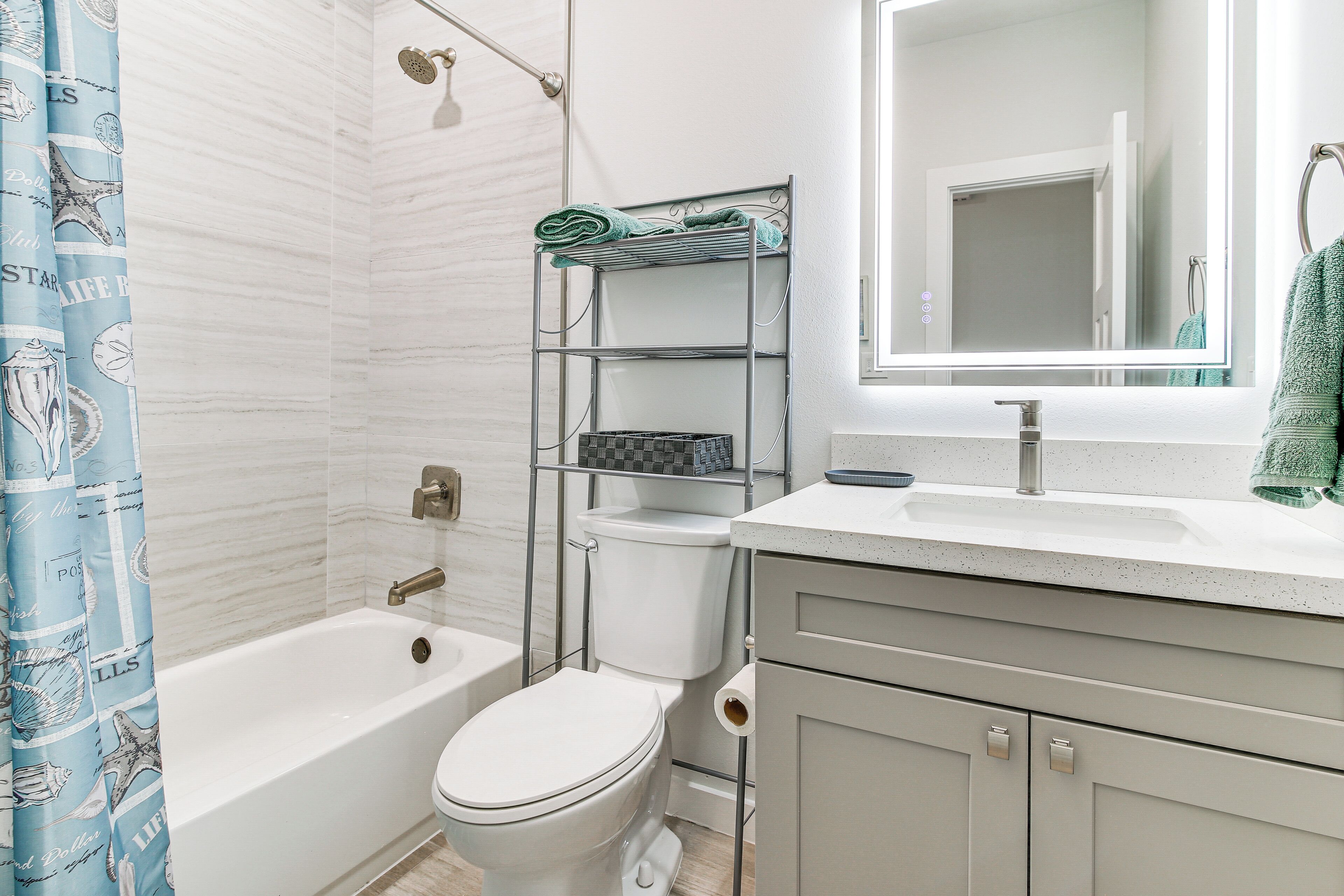 Une salle de bain avec une baignoire, des toilettes et une étagère en métal où sont rangées les serviettes.
