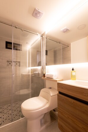 A modern bathroom with a glass-enclosed shower, a white toilet, and a wooden vanity. - Mishka Hotel Boutique (Cartagena)