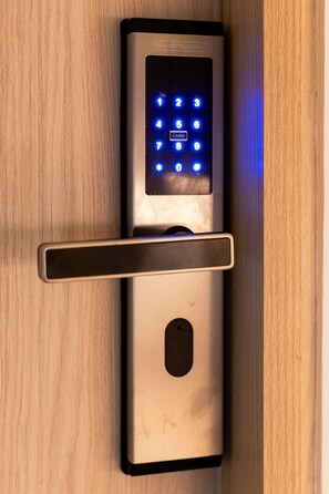A modern door lock with a keypad and a card slot, mounted on a wooden door. - Mishka Hotel Boutique (Cartagena)