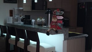 A modern kitchen with a central island, bar stools, pendant lights, and a refrigerator. - Mishka Hotel Boutique (Cartagena)