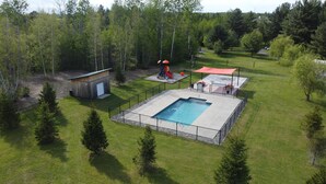 An aerial view of a residential area with a swimming pool, a small shed, and a playground. - Domaine Yamaska (Bromont)