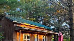 A rustic cabin with a porch, a picnic table, and a grill. - Domaine Yamaska (Bromont)