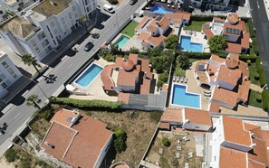 Ett bostadsområde med flera hus, där varje hus har en egen swimmingpool och ett tak täckt med takpannor.