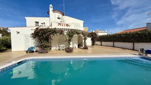 En vit byggnad med en pool, satellitantenner och en täckt uteplats.