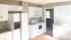 A kitchen with white cabinets, a refrigerator, a microwave, an oven, and a dishwasher.