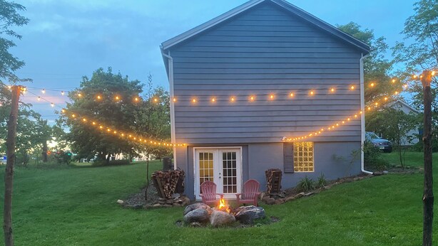 A house with a porch, a fire pit, and string lights.