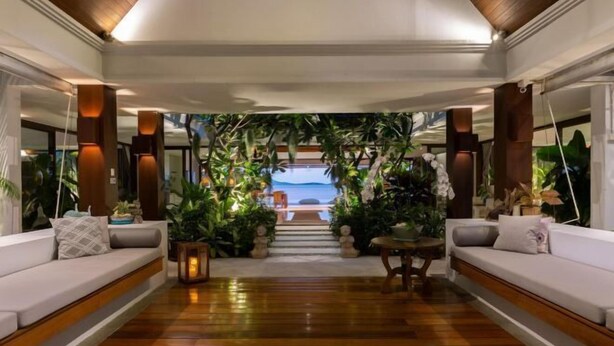 A hallway with a wooden floor, white sofas, and a view of the ocean through a glass door. - Chic Baan Capo - Luxury Four Bedroom Beachfront Villa (Koh Samui)