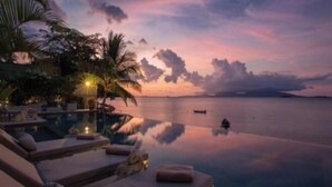 An infinity pool with lounge chairs and a sunset view. - Chic Baan Capo - Luxury Four Bedroom Beachfront Villa (Koh Samui)