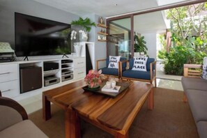 A modern living room with a flat-screen TV, wooden coffee table, and a sofa with cushions. - Chic Baan Capo - Luxury Four Bedroom Beachfront Villa (Koh Samui)